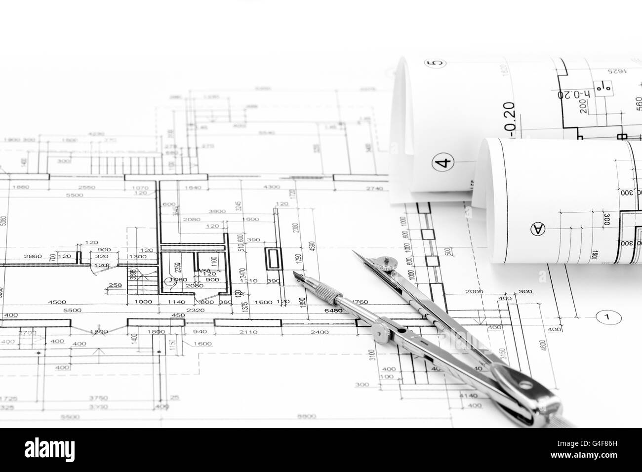 Rollen der Architekturpläne und Haus-Plan mit dem Kompass zeichnen Stockfoto
