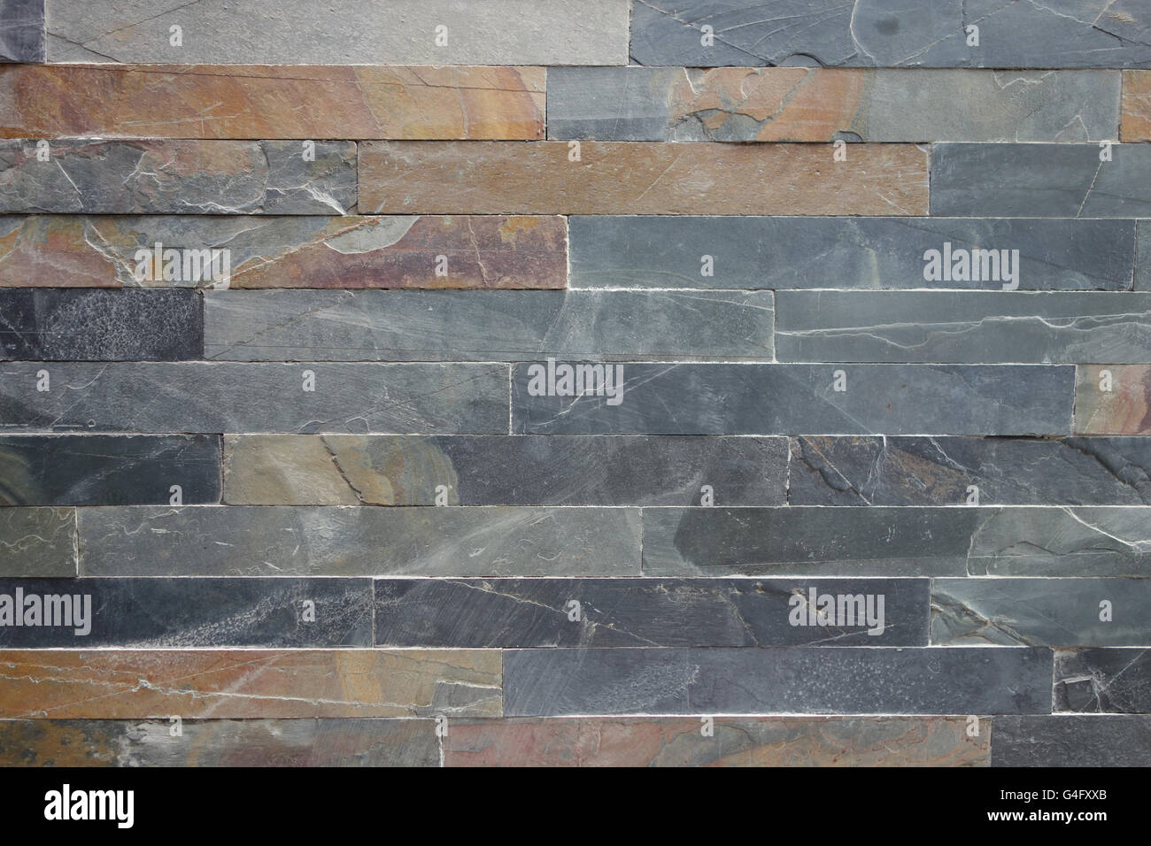 Grob strukturierte Stein Verkleidung Fliesenwand in grau und Ocker Farben Hintergrund Stockfoto