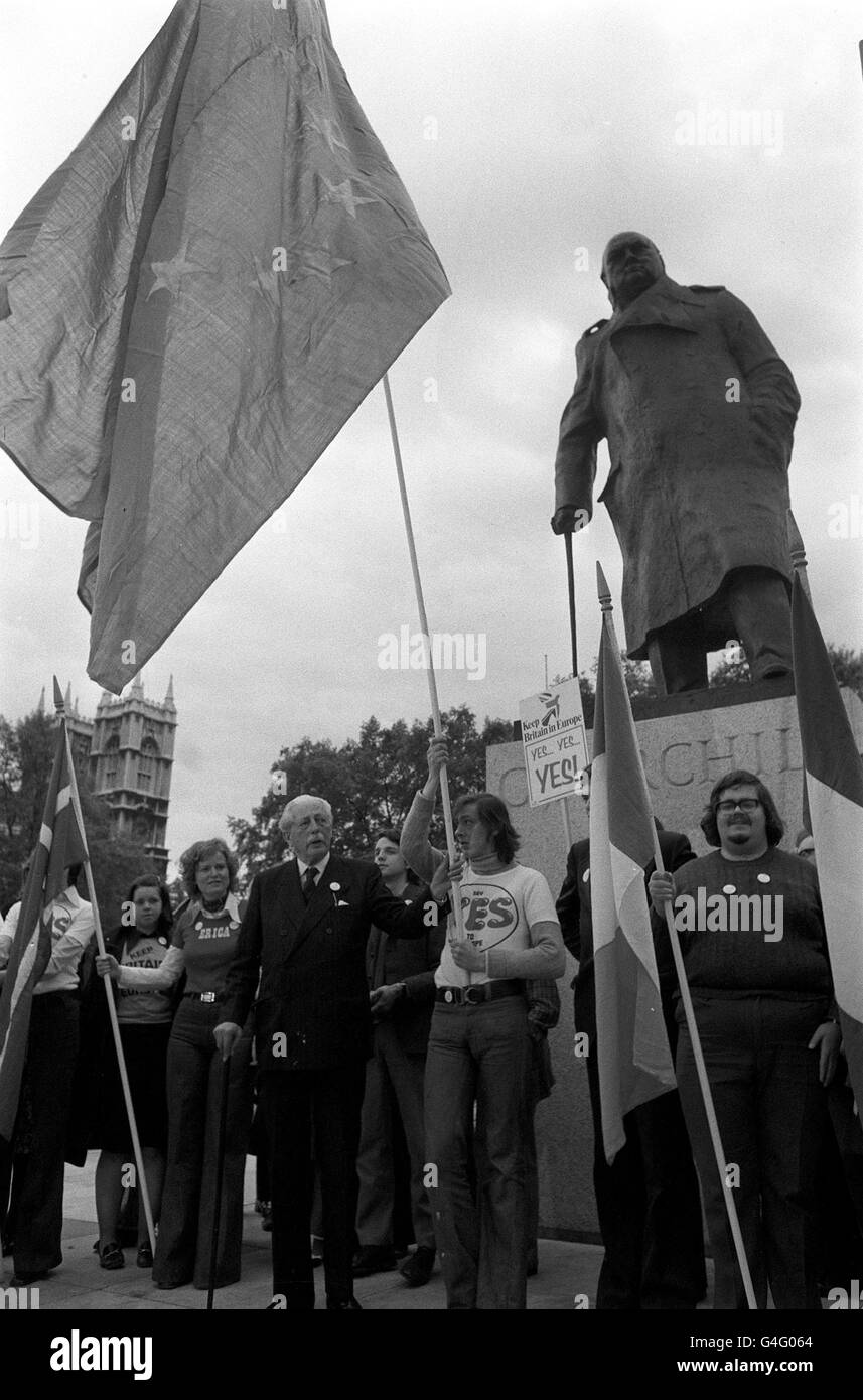 Harold Macmillan übergibt seinem Enkel Adam Macmillan unter der Statue von Sir Winston Churchill auf dem Parliament Square in London einen europäischen Standard. Stockfoto