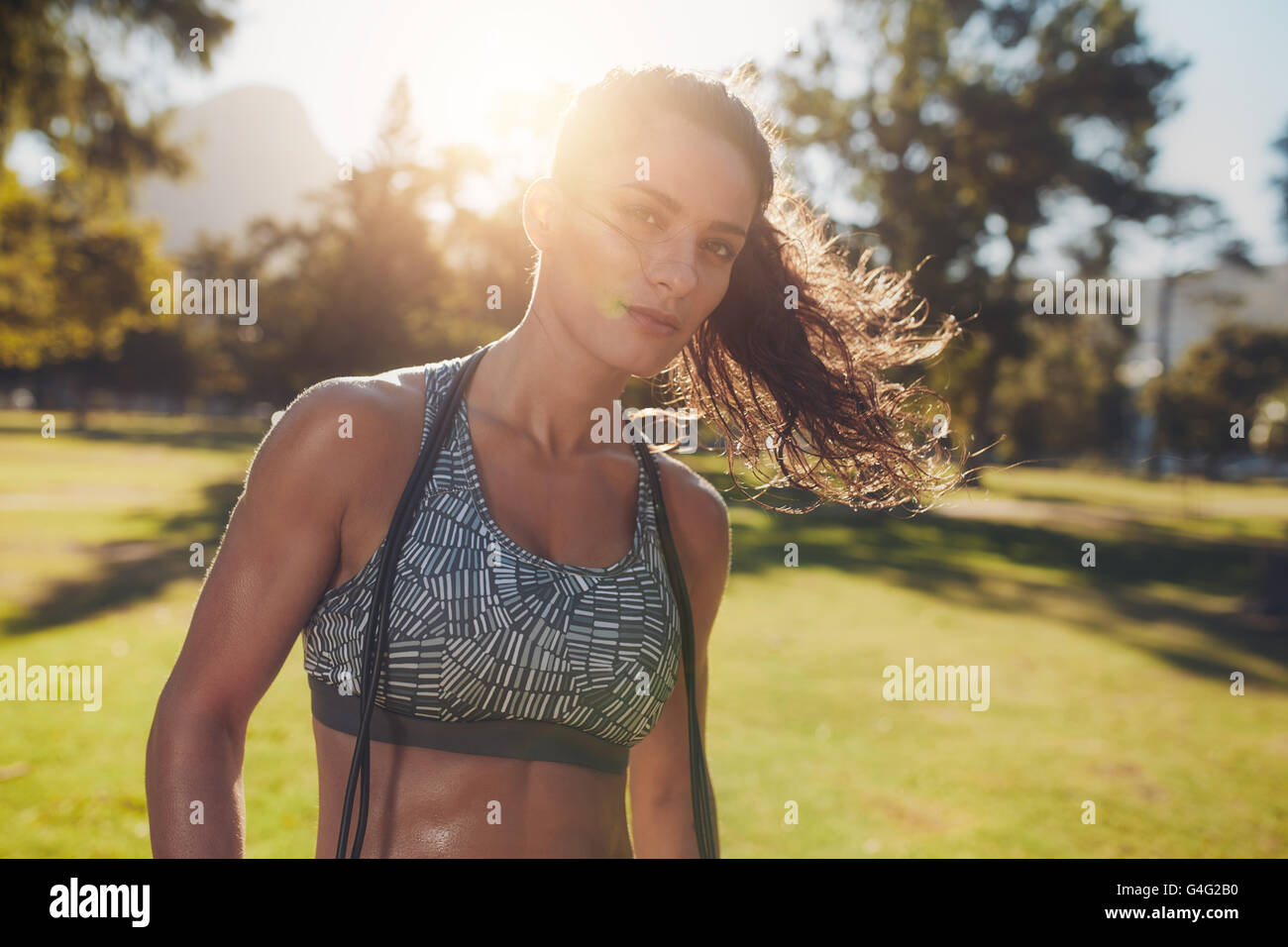 Porträt von gesunden jungen Frau im Sport-BH mit einem Springseil um den Hals. Weibliche Athleten, die eine Pause von Fitness-t Stockfoto