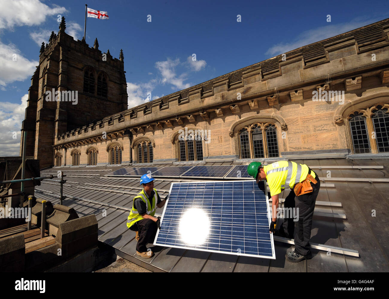 Bauleiter Andy Wilkinson (links) und Senior Installer Keith Hodgson arbeiten am Dach der Bradford Cathedral, die als erste Kathedrale der Welt Solarmodule auf ihrem alten Dach installiert hat. 42 Paneele werden am Dach des Südtransepts angebracht, um es energieautark zu machen. Stockfoto