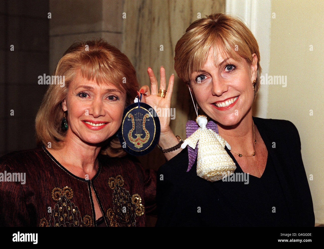 PA News 5/1/99 der Ex-BBC-Newsreader Jan Leeming (links) und die Moderatorin der „Holiday“-Fernsehsendung Suzanne Dando mit einer von Zandra Rhodes entworfenen Fee bei einer Versteigerung von Weihnachtsdekorationen, die die Königin zugunsten der Wohltätigkeitsorganisation „The Society of Stars“ anbietet. Die Auktion fand im Victoria and Albert Museum, London, statt. Stockfoto