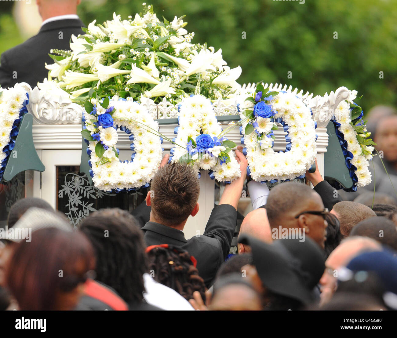 Trauernde platzieren Blumen auf einer Pferdekutsche nach der Beerdigung des Polizeitopfer Mark Duggan in der New Testament Church of God in Wood Green, Nord-London. Stockfoto