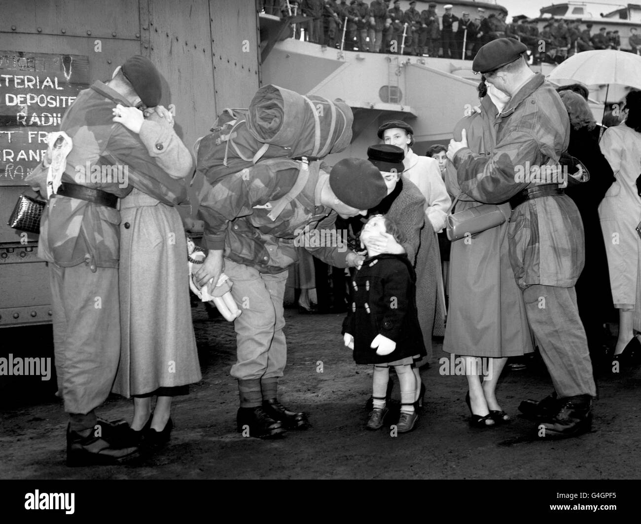 Jacqueline begrüßt ihren Vater, Color-Sergeant Berkeley vom Royal Marines Commando, als er von Port Said, Ägypten, nach Plymouth zurückkehrte. Er und andere Marineinfanteristen waren an Bord der Light Fleet Carrier HMS Ocean. Weitere Mitglieder des Commando begrüßen ihre Frauen, DJ Crewe aus Portsmouth (links) und G. Rollinson aus Liverpool. Stockfoto