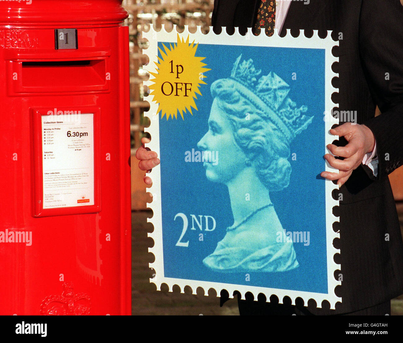 Richard Dykes, Geschäftsführer von Royal Mail, hält im Postamt in London einen riesigen Stempel der zweiten Klasse in die Höhe, nachdem Royal Mail den Preis für einen Posten der zweiten Klasse um einen Cent auf 19 Cent gesenkt hatte und schwor, den Preiseinfrieren für den Basispreis der ersten Klasse von 26 cent fortzusetzen. Stockfoto
