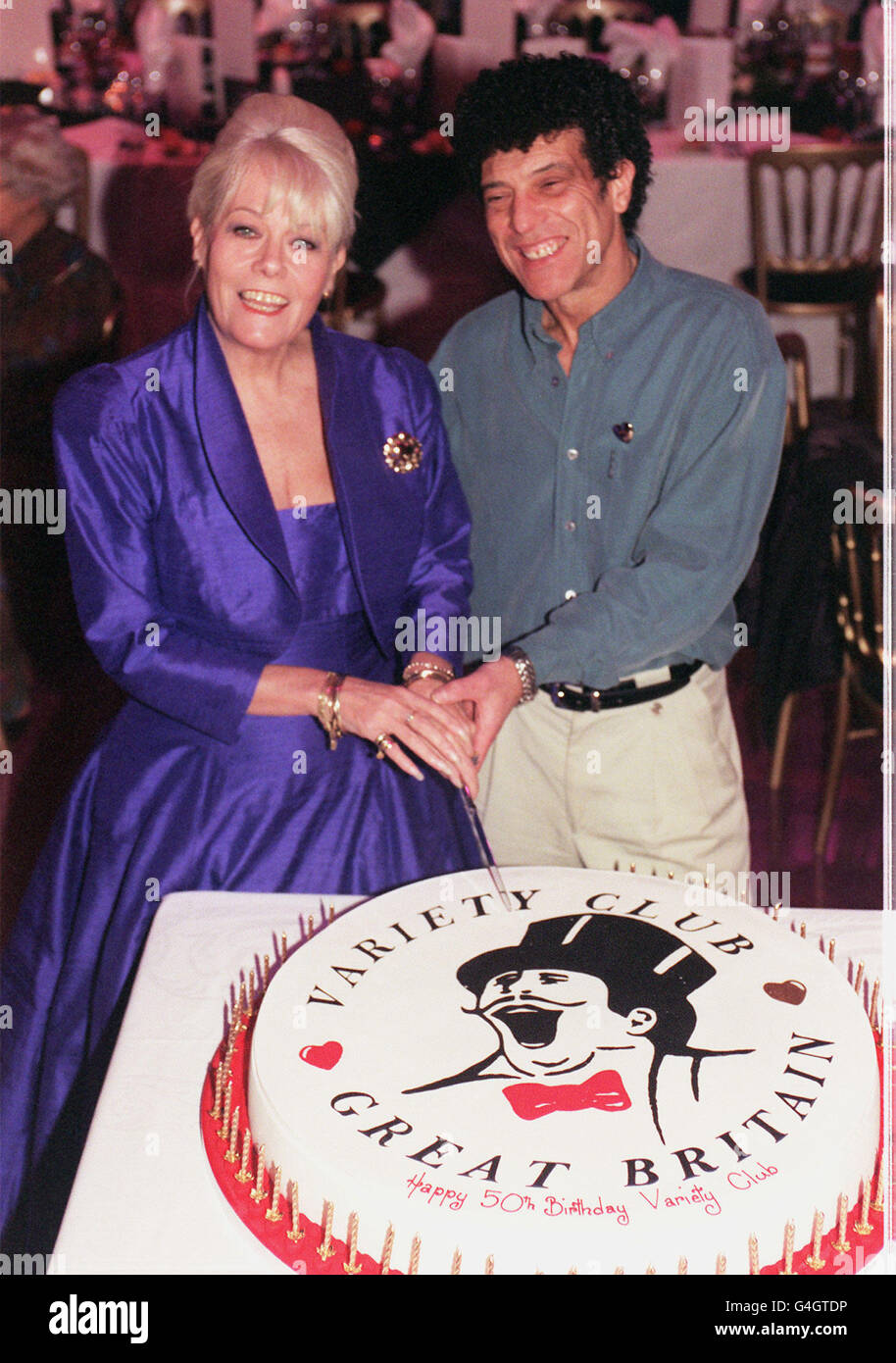 Die Schauspielerin Wendy Richard und der Sänger Ray Dorset von der 70er-Jahre-Band Mungo Jerry schnitten den Kuchen, um den 50. Jahrestag des Variety Club of Great Britain zu feiern, beim Start des Gold Heart Day Appeal 1999 der Organisation. Stockfoto