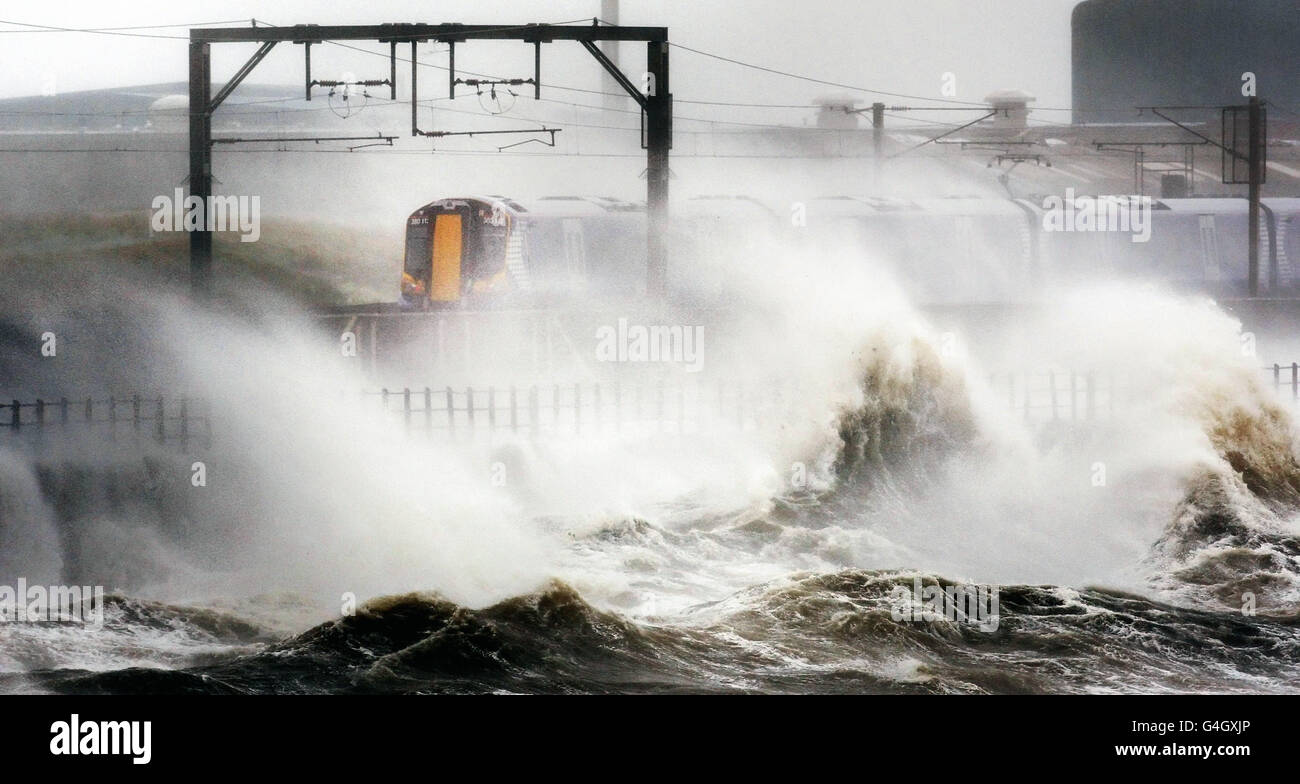 Ein Zug fährt durch starke Winde, während hohe Wellen die Küste in der Nähe von Saltcoats, North Ayrshire, schlagen, während die Überreste des Orkans Katia die britischen Küsten treffen. Stockfoto