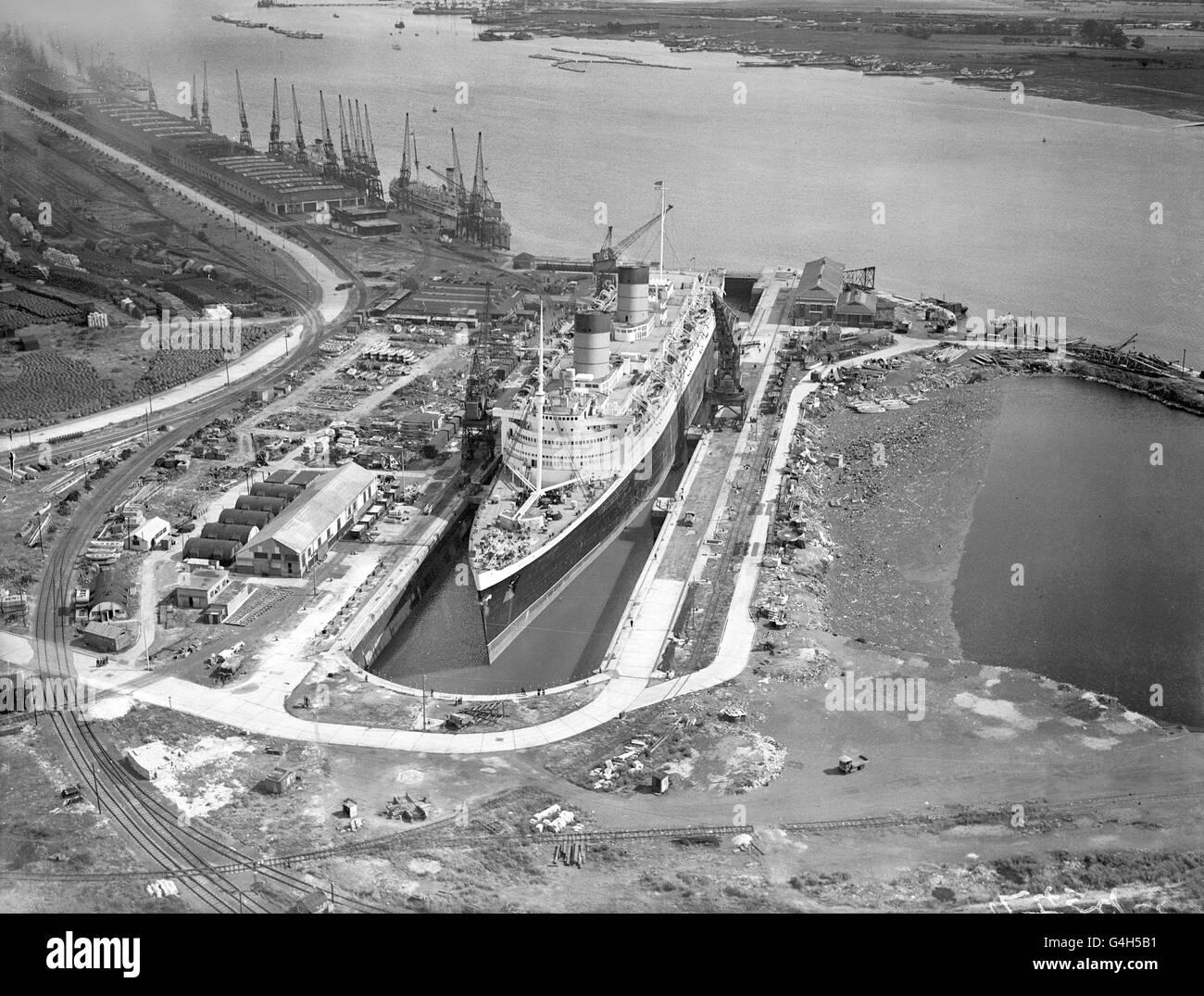 Die 85,000 Tonnen schwere 'Queen Elizabeth' nimmt fast den gesamten Bereich des riesigen King George V Docks in Southampton ein. Das riesige Schiff wird von seiner Rolle als Truppenschiff im Krieg zu seiner Rolle als Luxuskreuzfahrtschiff in der Friedenszeit umgerüstet. Stockfoto