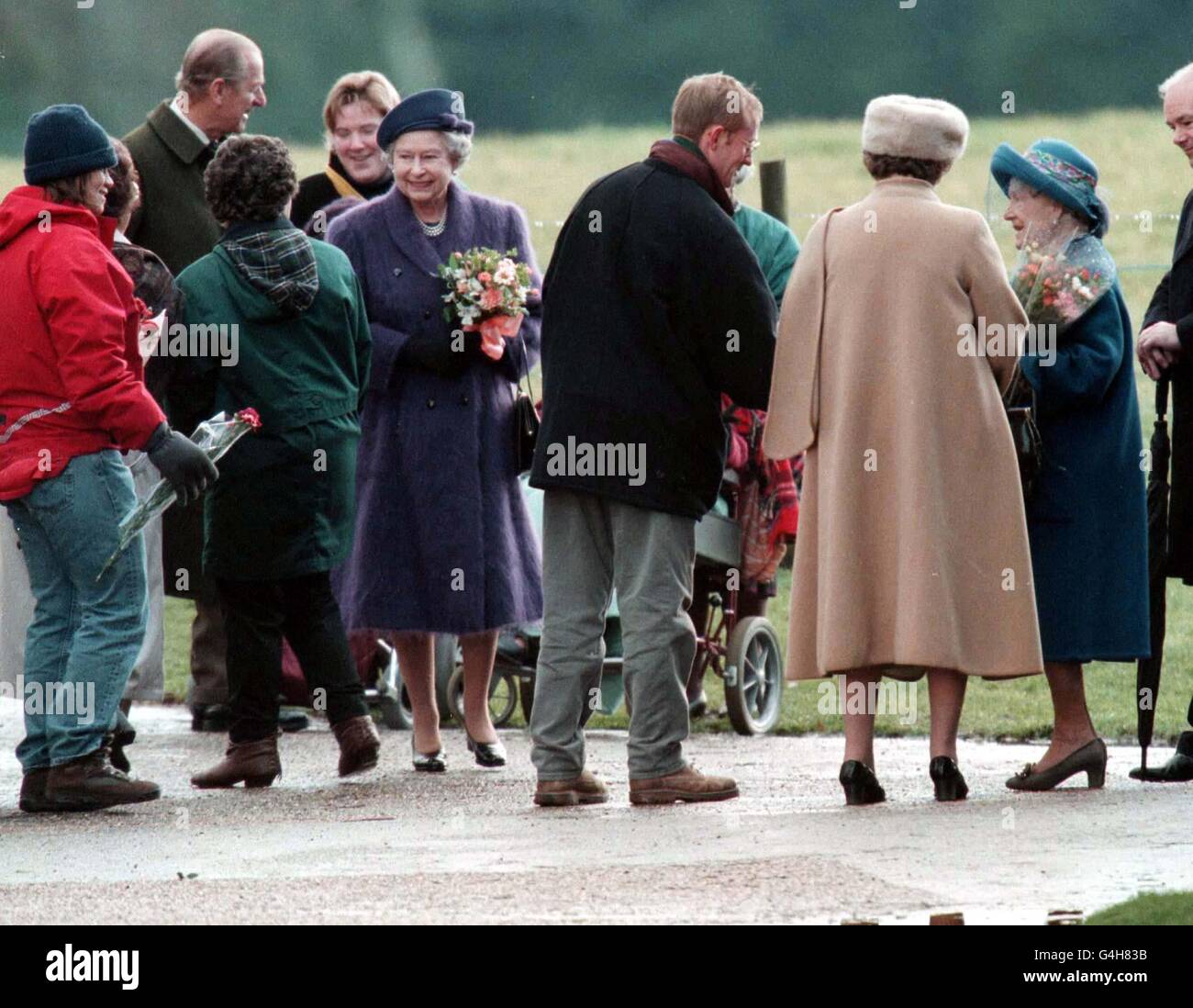 Ihre Majestät die Königin (Mitte mit Blumen), die Königin Mutter (rechts) und der Herzog von Edinburgh (links) unterhalten sich mit den Massen, während sie heute (Sonntag) einen Gottesdienst in Sandringham verlassen. Foto von Toby Melville/PA. Stockfoto