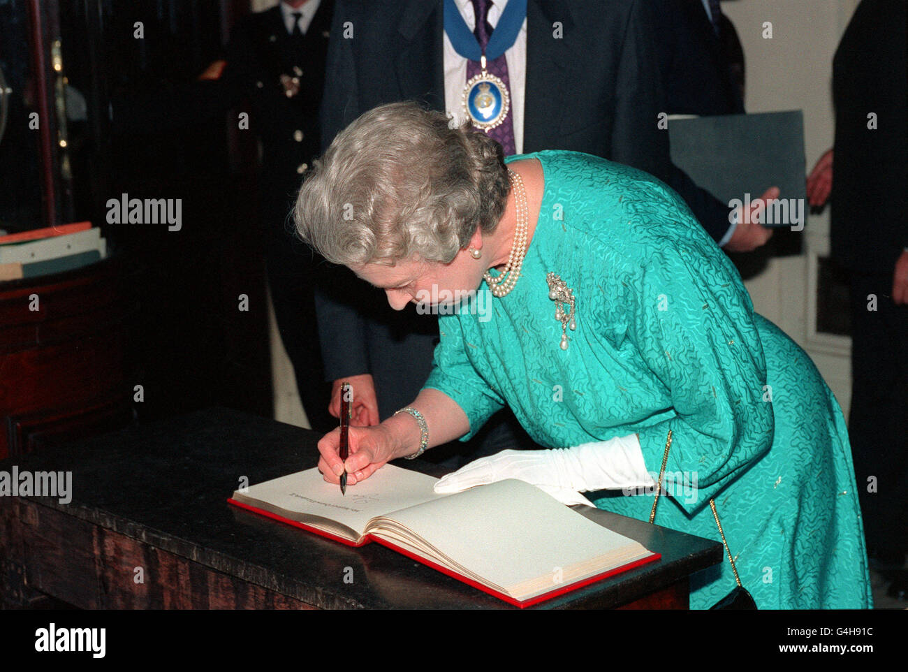 PA NEWS PHOTO 26/5/93 DIE KÖNIGIN UNTERSCHREIBT IN DER ROYAL GEOGRAPHICAL SOCIETY IN LONDON DAS BERÜHMTE BESUCHERBUCH, WO SIE AN EINEM EMPFANG ZUM GEDENKEN AN DEN VIERZIGSTEN JAHRESTAG DER EROBERUNG DER EVEREST-EXPEDITION TEILNAHM Stockfoto