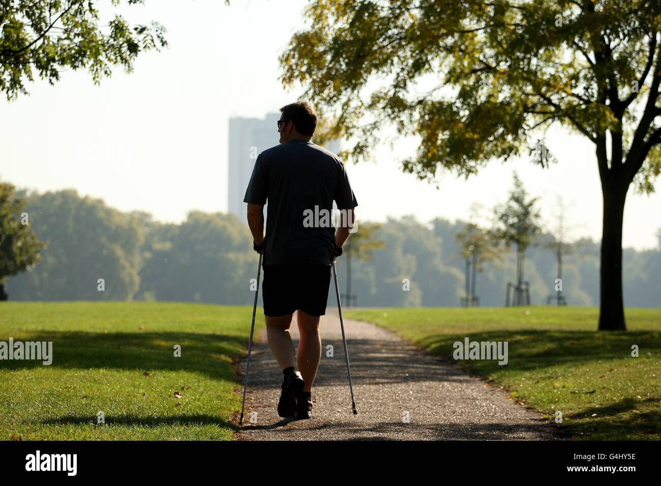 Ein Delegierter bei der jährlichen INWA (International Nordic Walking Federation) Tagung im Londoner Hyde Park, der das ungewöhnlich warme Wetter genießt. Stockfoto