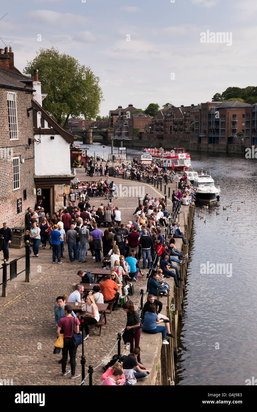 Viele Leute trinken und entspannen im geschäftigen Pub am Fluss (King's Arms) und Freizeitbooten auf dem Fluss Ouse - King's Staith, York, North Yorkshire, England. Stockfoto