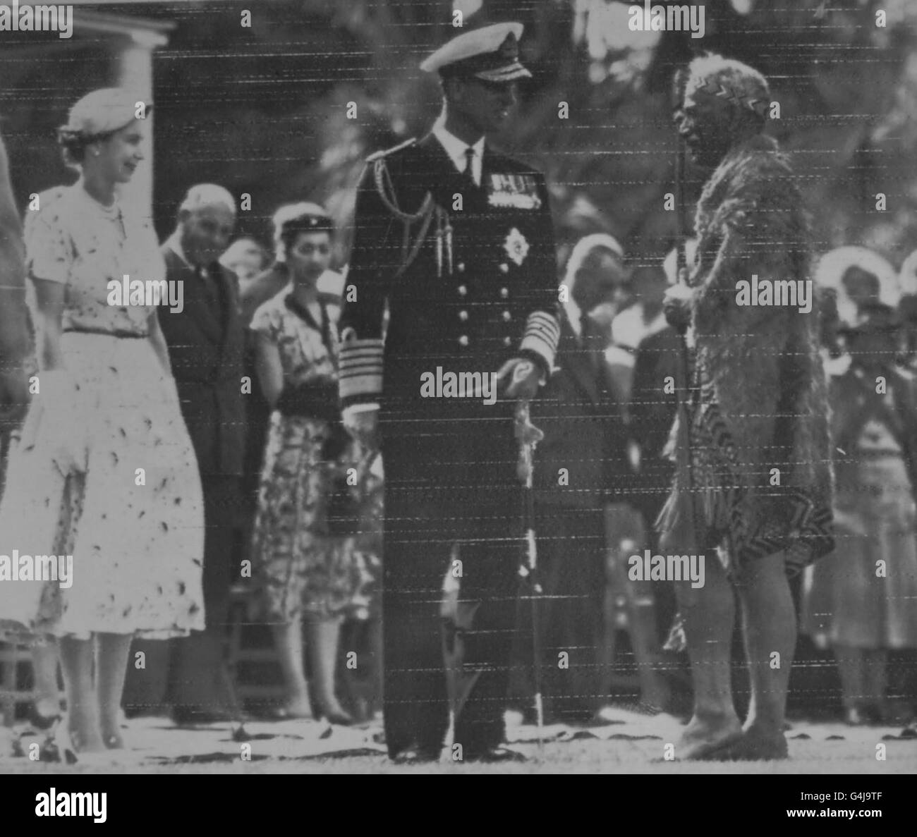 Die Königin und der Herzog von Edinburgh werden vom federgetarntem Maori-Häuptling Henare Toka begrüßt, als sie die Maori und ihre Häupter in Waitangi, Neuseeland, besuchten. Stockfoto