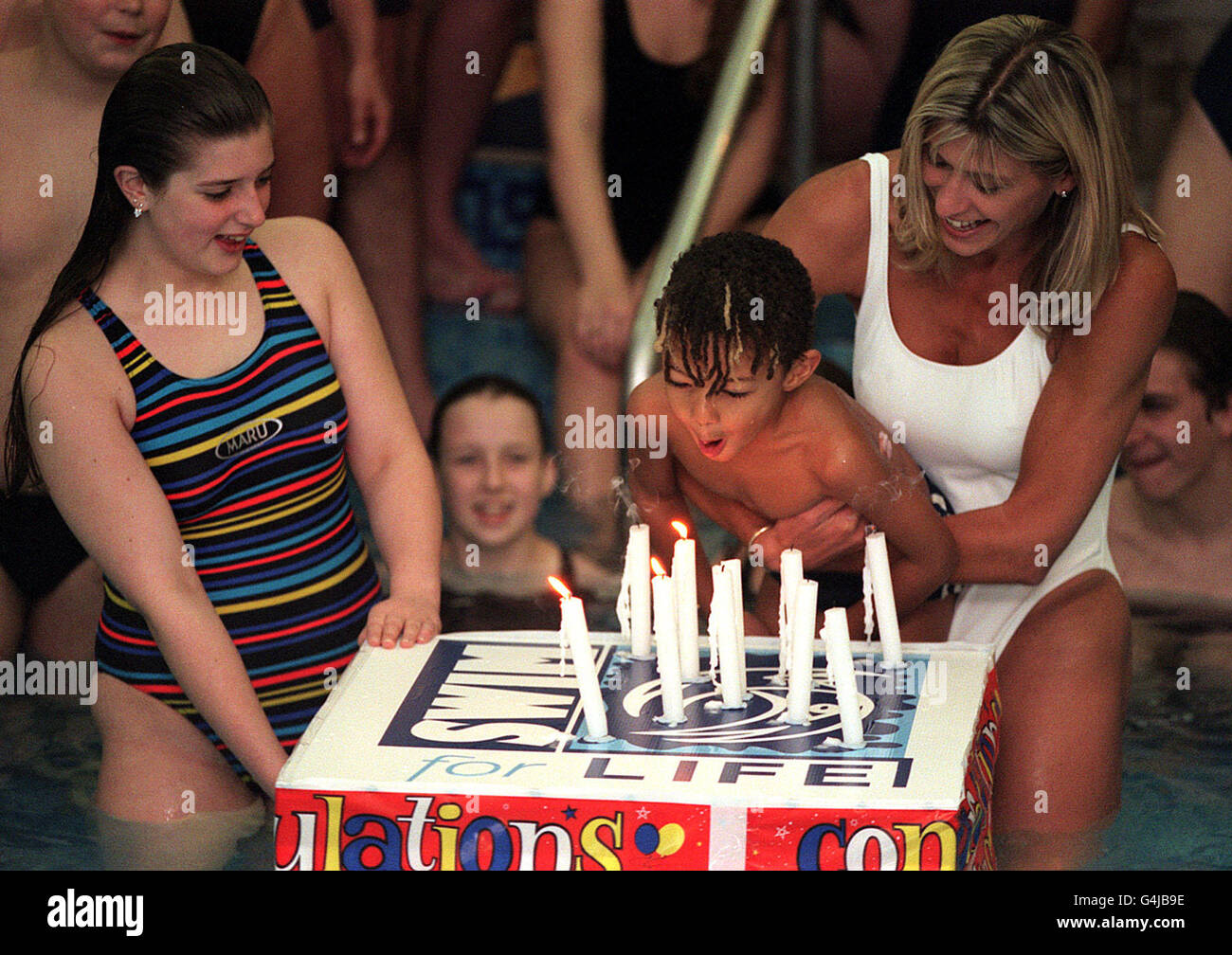 Die ehemalige Olympiaschwimmerin Sharron Davies hält ihren Sohn Elliott im Marriot Hotel in Marble Arch, London, fest, als er die Kerzen ausbläst, um die Mile Swim Challenge zugunsten des Imperial Cancer Research Fund zu starten. Stockfoto