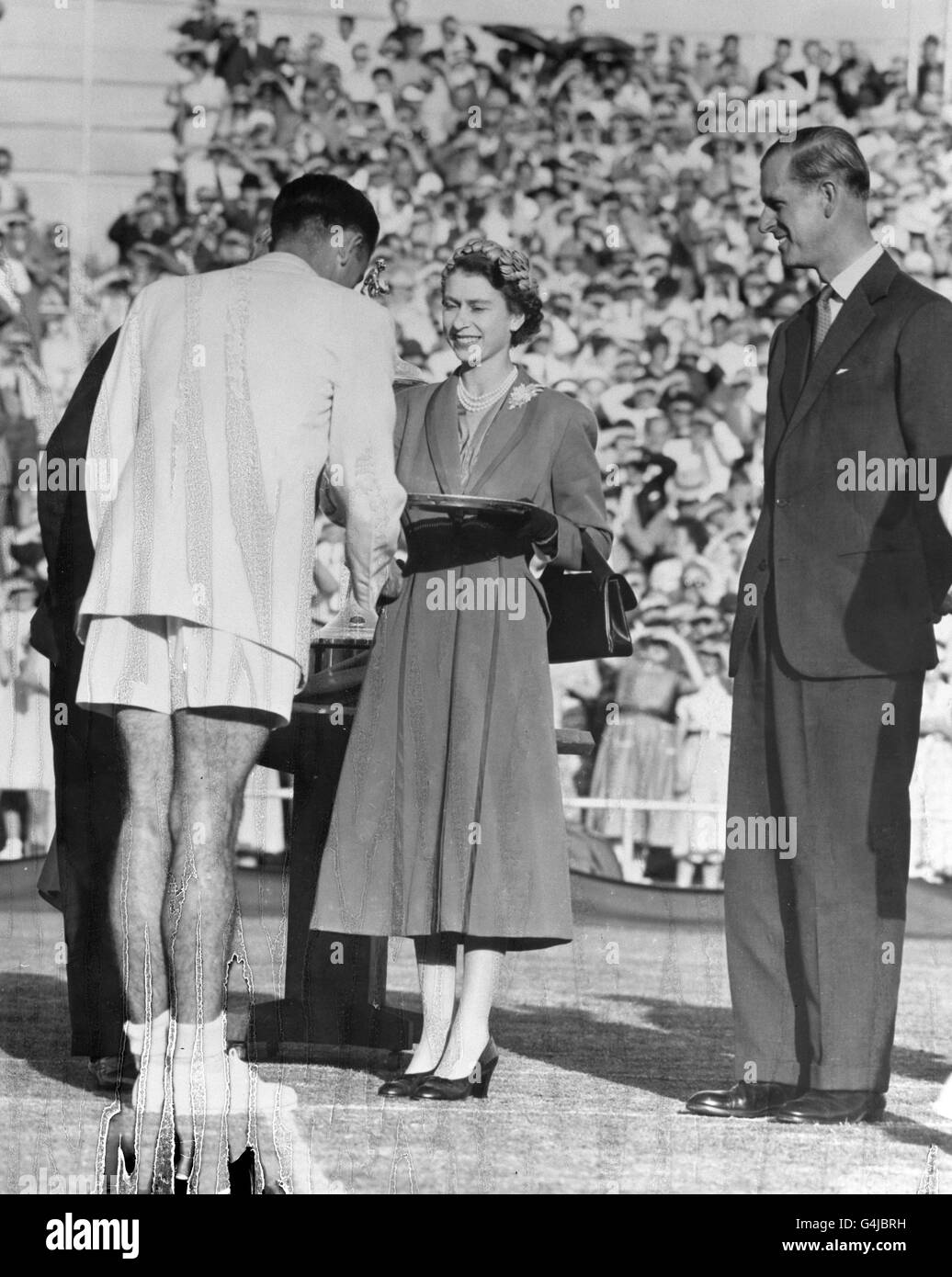 Die Königin, die vom Duke of Edinburgh beobachtet wird, präsentiert dem jungen australischen Tennisstar Mervyn Rose während des Rouyal-Besuchs auf den Kooyong Tennisplätzen in Melbourne einen Salver. *beschädigte Platte* Stockfoto