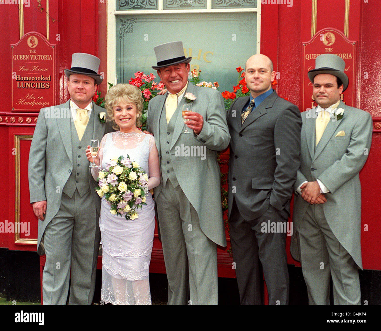 EastEnders spielt Barbara Windsor (die Braut „Peggy Mitchell“ spielt) und Mike Reid (Bräutigam „Frank Butcher“, Dritter von links) mit Co-Stars während einer Fotowand vor dem Queen Vic Pub in den Londoner Elstree Studios, wo ihr Hochzeitsempfang auf dem Bildschirm gefilmt wurde. * mit anderen Schauspielern (l-r) Steve McFadden (Phil), Ross Kemp (Grant) und Shaun Williamson (Barry). Stockfoto