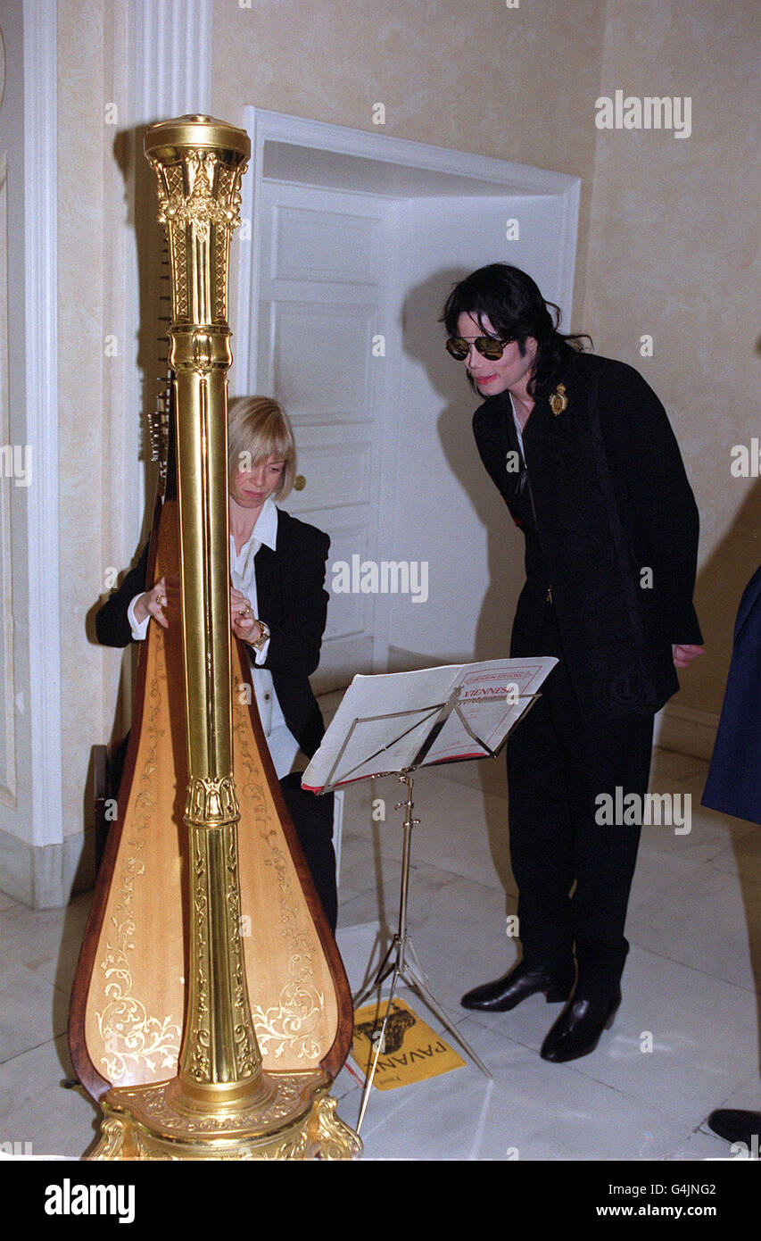 Popstar Michael Jackson (R) hört zu, wie Rhian Willia eine große Goldarfe spielt, während er im Harrods-Kaufhaus in Knightsbridge, London, war. Stockfoto