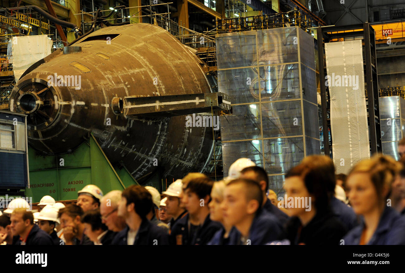 Arbeiter stehen vor der im Bau befindlichen HMS Wadacious, während sie eine Zeremonie zum Beginn der Hauptbauphase von HMS Anson auf der BAE Systems Submarine Solutions Werft in Barrow-in-Furness, Cumbria, beobachten. Stockfoto