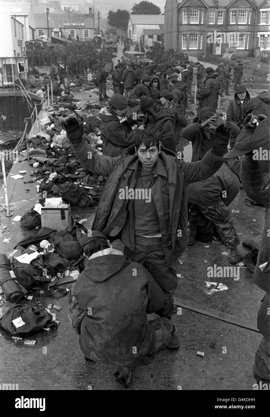 DER FALKLAND-KRIEG: Argentinische Gefangene werden von britischen Fallschirmjägern und Royal Marines in Port Stanley durchsucht, bevor sie während des Falkland-Konflikts zurückgeführt werden. Stockfoto