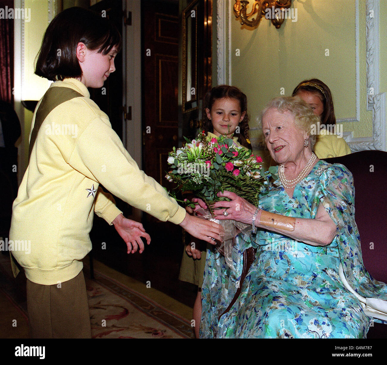 Königin Elizabeth, der Mutter der Königin, wird von Rebecca Heaton aus Beckenham, im Südosten Londons, ein Blumenstrauß überreicht, als sie am Empfang der Commonwealth-Kommissare der Guide Association im Marlborough House in London teilnahm. Stockfoto
