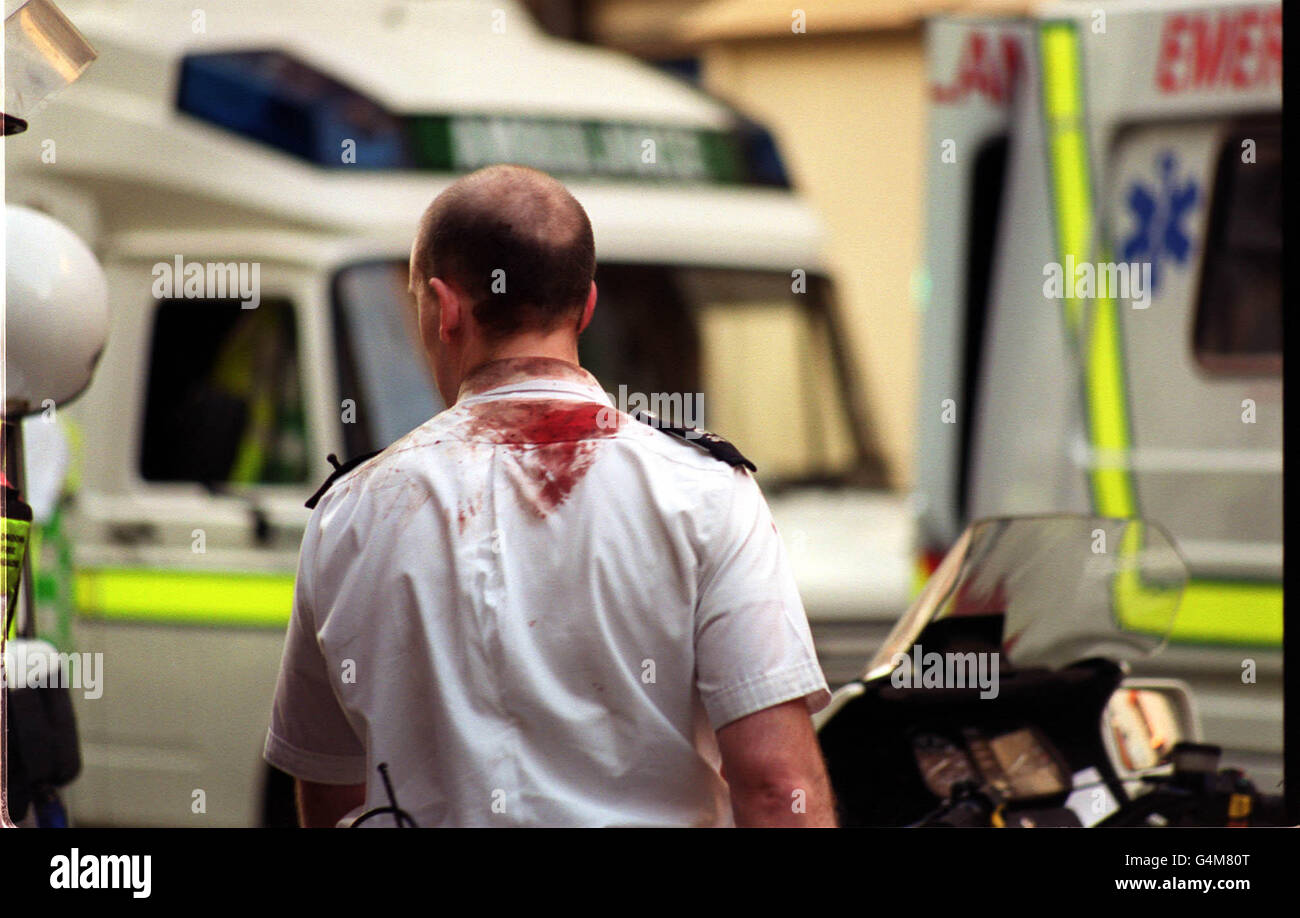 Ein blutgetränkter Polizeibeamter besucht die Szene in der Old Compton Street in Soho, im Zentrum von London, nach einem Bombenanschlag. Mindestens 2 Menschen wurden getötet und 73 Menschen wurden nach einer Explosion ohne Vorwarnung im Admiral Duncan Pub, einer beliebten Schwulenbar, verletzt. Stockfoto