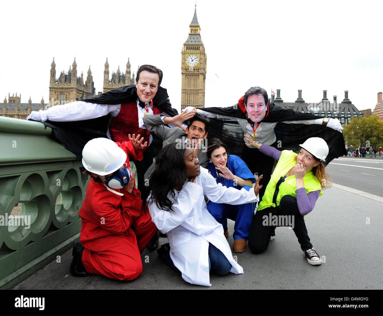 Zwei Unison-Demonstranten mit David Cameron und Nick Clegg maskiert als Vampire, während einer Fotozelle auf der Westmister Bridge im Zentrum von London, Nehmen Sie einen "Bissen" aus dem öffentlichen Sektor Arbeitnehmer zu betonen, die Behauptung der Gewerkschaft, dass jeder fünfte Menschen leiden wird, wenn die Regierung führt ihre öffentlichen Sektor Rentenreform. Stockfoto