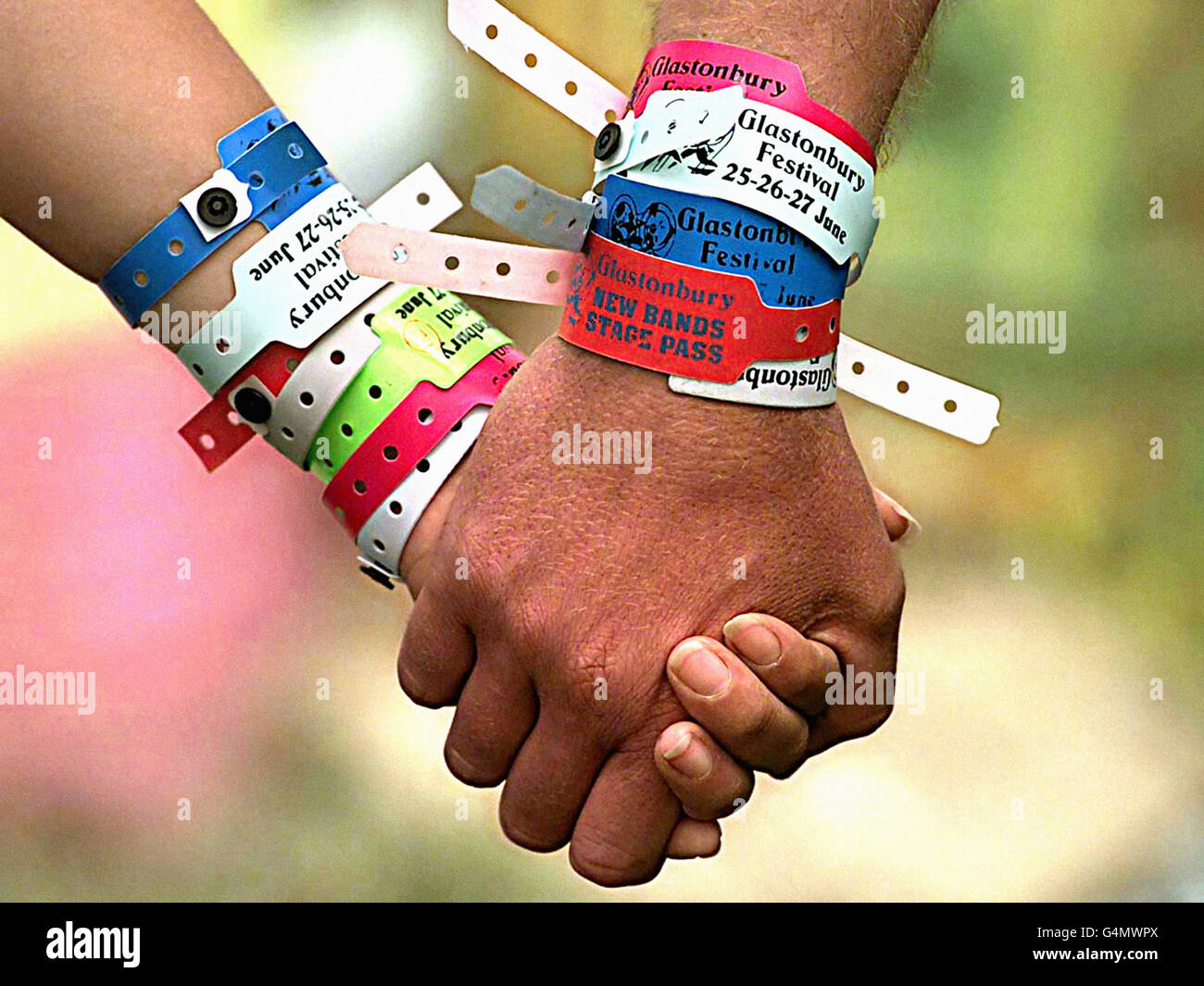 Ein Paar Festivalbesucher mit zahlreichen Armbandspässen beim Glastonbury Festival. Stockfoto