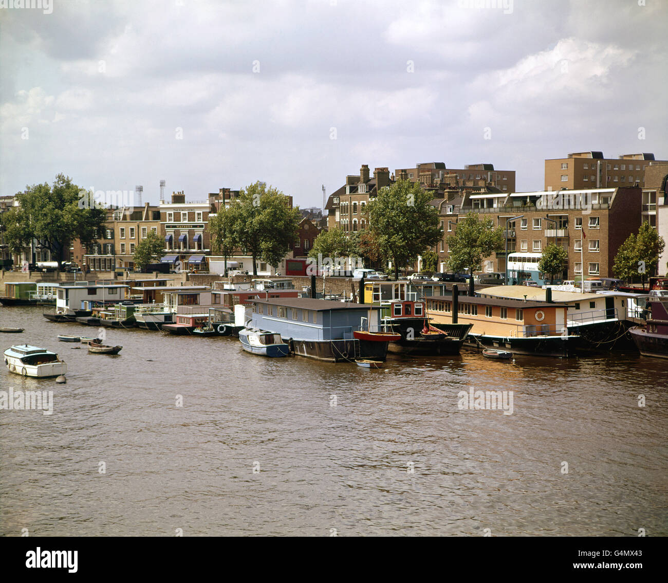 Schwimmende Häuser und kleine Boote, die am Cheyne Walk im Londoner Chelsea-Viertel festgemacht sind. Die Flutlichter der Stamford Bridge, Heimat des Chelsea Football Clubs, sind in der Ferne zu sehen Stockfoto