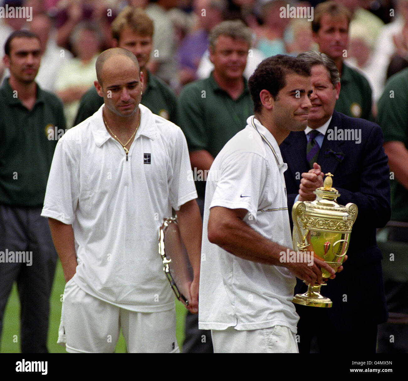 Keine kommerzielle Nutzung. Der Amerikaner Pete Sampras (R) hält die Champion's Trophy, während der besiegte Andre Agassi nach dem Herren-Einzel-Finale bei den Wimbledon Tennis Championships 1999 niedergeschlagen wirkt. Sampras besiegte Agassi 6-3 6-4 mit 7:5. Stockfoto