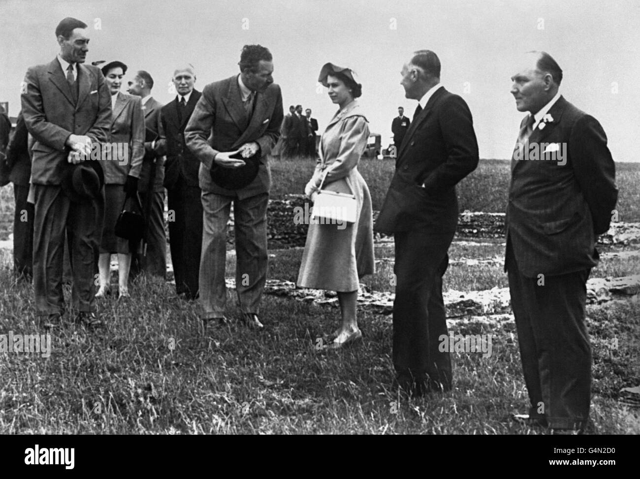 Königin Elisabeth II. Auf dem Gipfel des Maiden Castle, ein altes Erdwerk aus der späten Steinzeit und der frühen Bronzezeit (ca. 2,000 v. Chr.) während ihres Besuchs im Hardy Country in Dorset. Mit der Königin ist Professor R.E.M Wheeler, der Archäologe, der an den Ausgrabungen im Bild arbeitet. Stockfoto