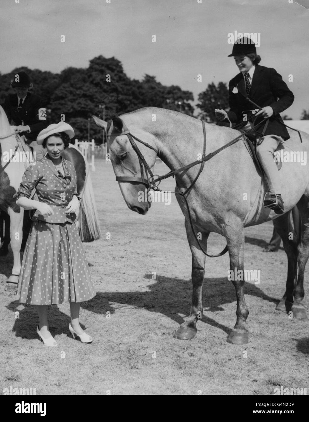 Königin Elizabeth II. Präsentiert einer Preisträgerin am ersten Tag der Royal Windsor Horse Show im Home Park im Schloss Windsor eine Rosette im Springwettbewerb der Klasse C. Stockfoto