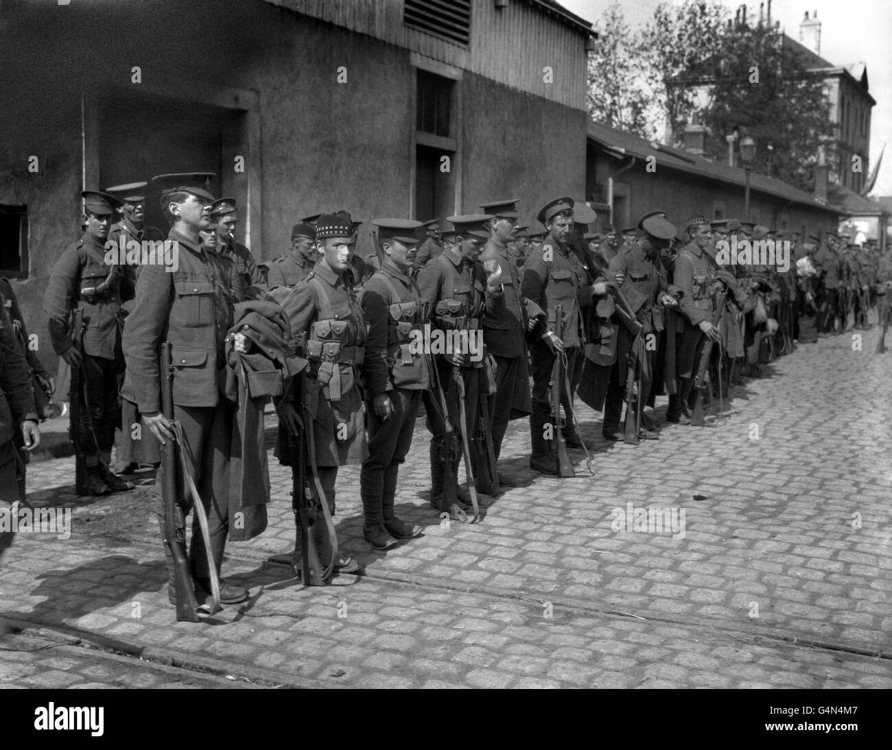 Britische "Tommies" verschiedener englischer und schottischer Regimenter, die während des Ersten Weltkriegs auf einer gepflasterten Straße in Frankreich auf dem Weg zur Front aufgestellt wurden. Stockfoto