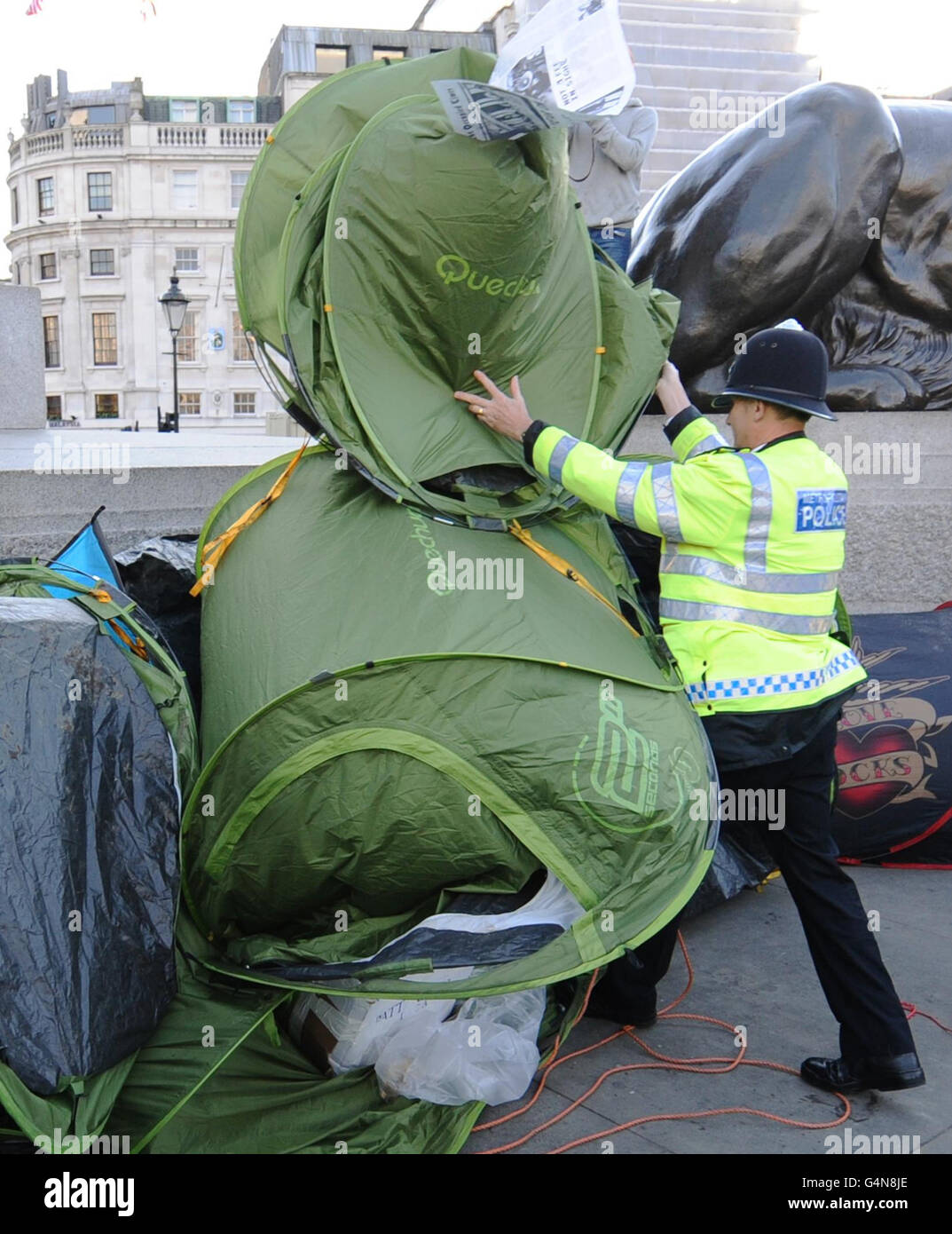 Ein Polizist entfernt ein Zelt, das während des letzten studentengeldes marsches von Demonstranten am Trafalgar Square in London als Teil eines Lagers aufgestellt wurde. Stockfoto