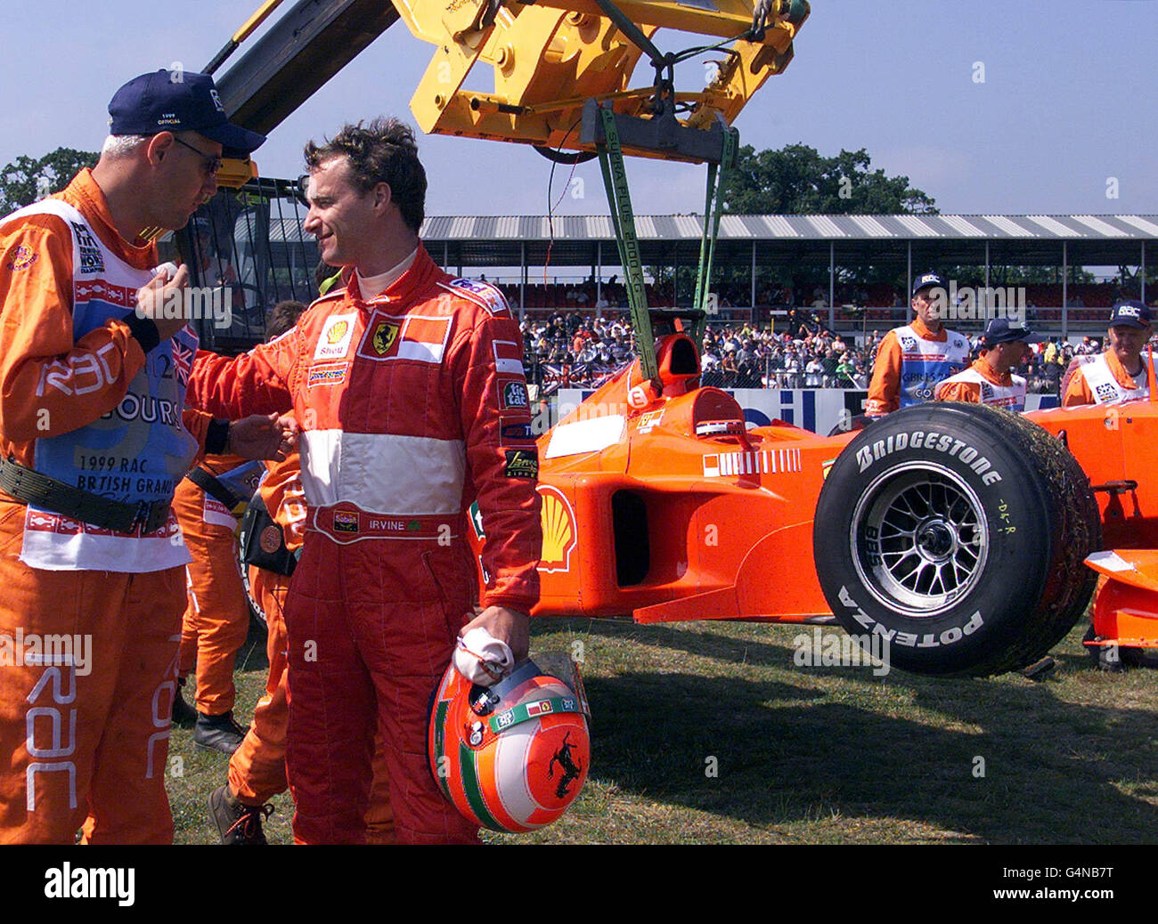 Edddie Irvine unterschreibt die Tabards eines Bahnbeamten, nachdem er in seinem Ferrari in Luffield Corner während des letzten Trainings für den Grand Prix von Großbritannien in Silverstone ausgedreht war. Stockfoto