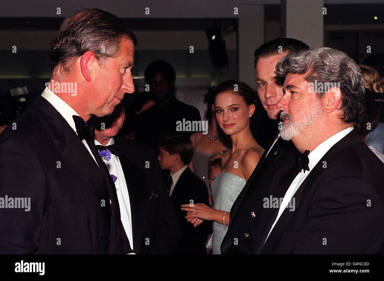 Prinz Charles (L) begrüßt Regisseur George Lucas (R), während die Stars Ewan (2. R) McGregor und Natalie Portman (3. R) die Royal Premiere von Star Wars: Episode 1, The Phantom Menace, am Leicester Square in London betrachten. Stockfoto