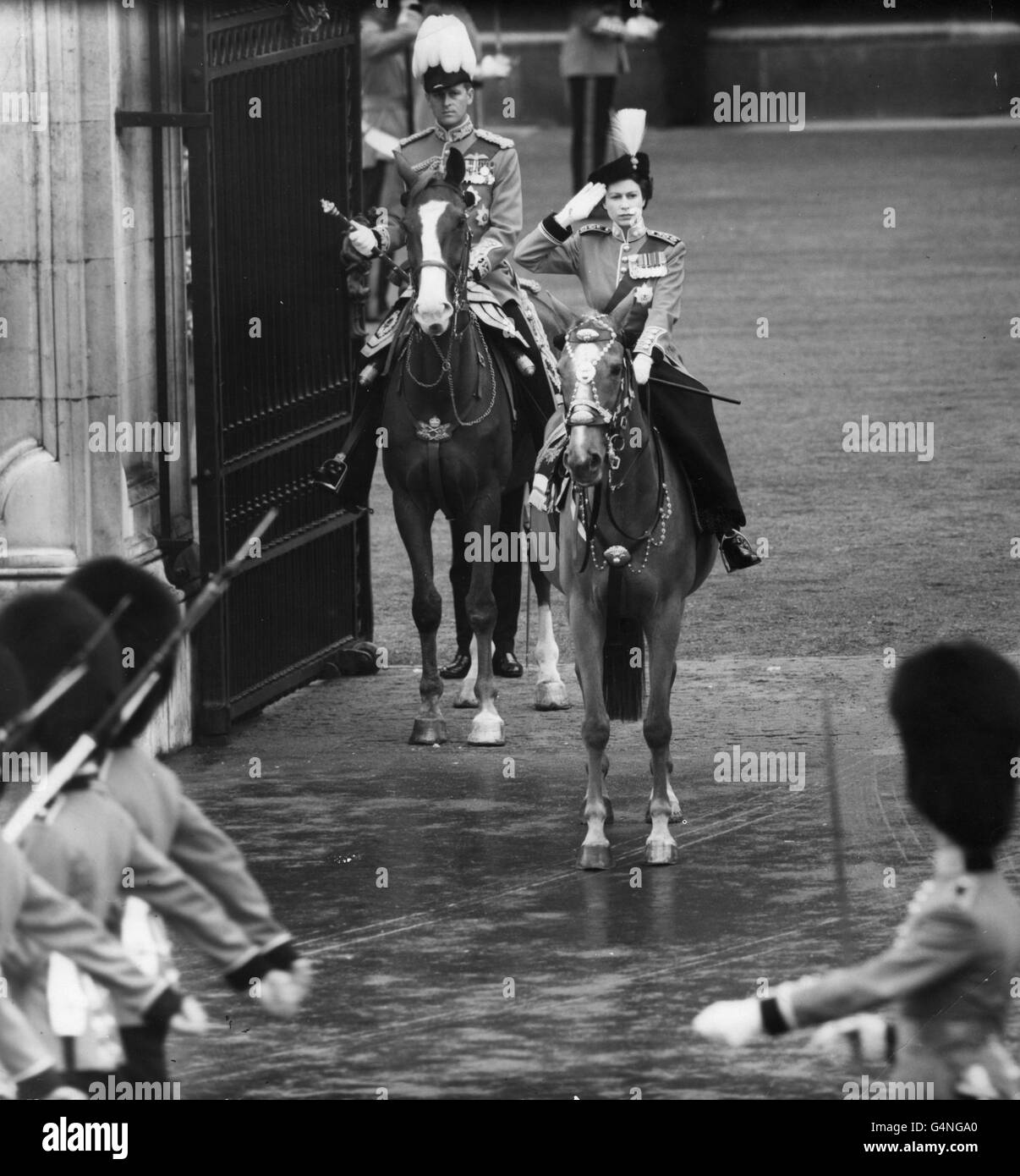 Königin Elizabeth II., die auf ihrem Pferd Winston reitet, grüßt vor den Toren des Buckingham Palace, als die Fußwächter der Hausbrigade vorbeimarschieren. Dahinter steht der Herzog von Edinburgh, in Feldmarschall-Uniform. Stockfoto