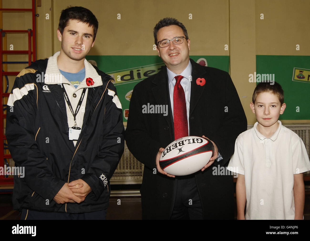 Der walisische Wohnungsminister Huw Lewis (Mitte) wird mit dem Trainer Gordon Ferguson (links) und dem Schüler Matthew Tran während eines Besuchs der Cadder Primary School in Glasgow abgebildet. Stockfoto