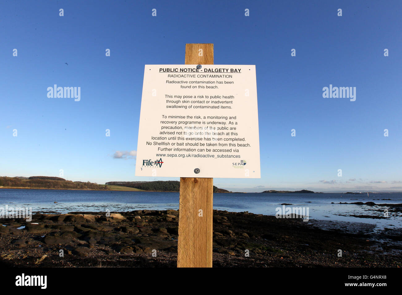 Ein Schild an der Dalgety Bay in Fife als ehemaliger Premierminister Gordon Brown hat das Verteidigungsministerium aufgefordert, sofort Maßnahmen zu ergreifen, um radioaktive Partikel am schottischen Strand zu behandeln. Stockfoto