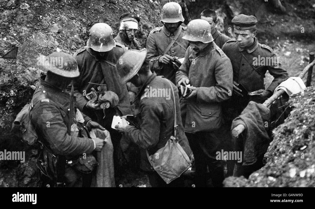 Britische Truppen sortieren in einem Graben die Habseligkeiten deutscher Gefangener, wobei Gegenstände in einen leeren Sandsack gelegt werden. Stockfoto