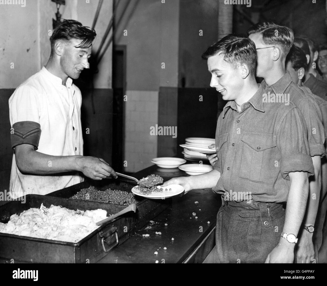 Der private David Shorey (rechts) aus Oxford führt die Kochhausanschlange für ein Essen für Männer der Oxfordshire und Buckinghamshire Light Infantry, die von der Ausreise nach Warley Barracks in der Nähe von Brentwood, Essex, zurückgerufen wurden - Teil der Maßnahmen, die in der Krise des Suez-Kanals ergriffen wurden. Stockfoto