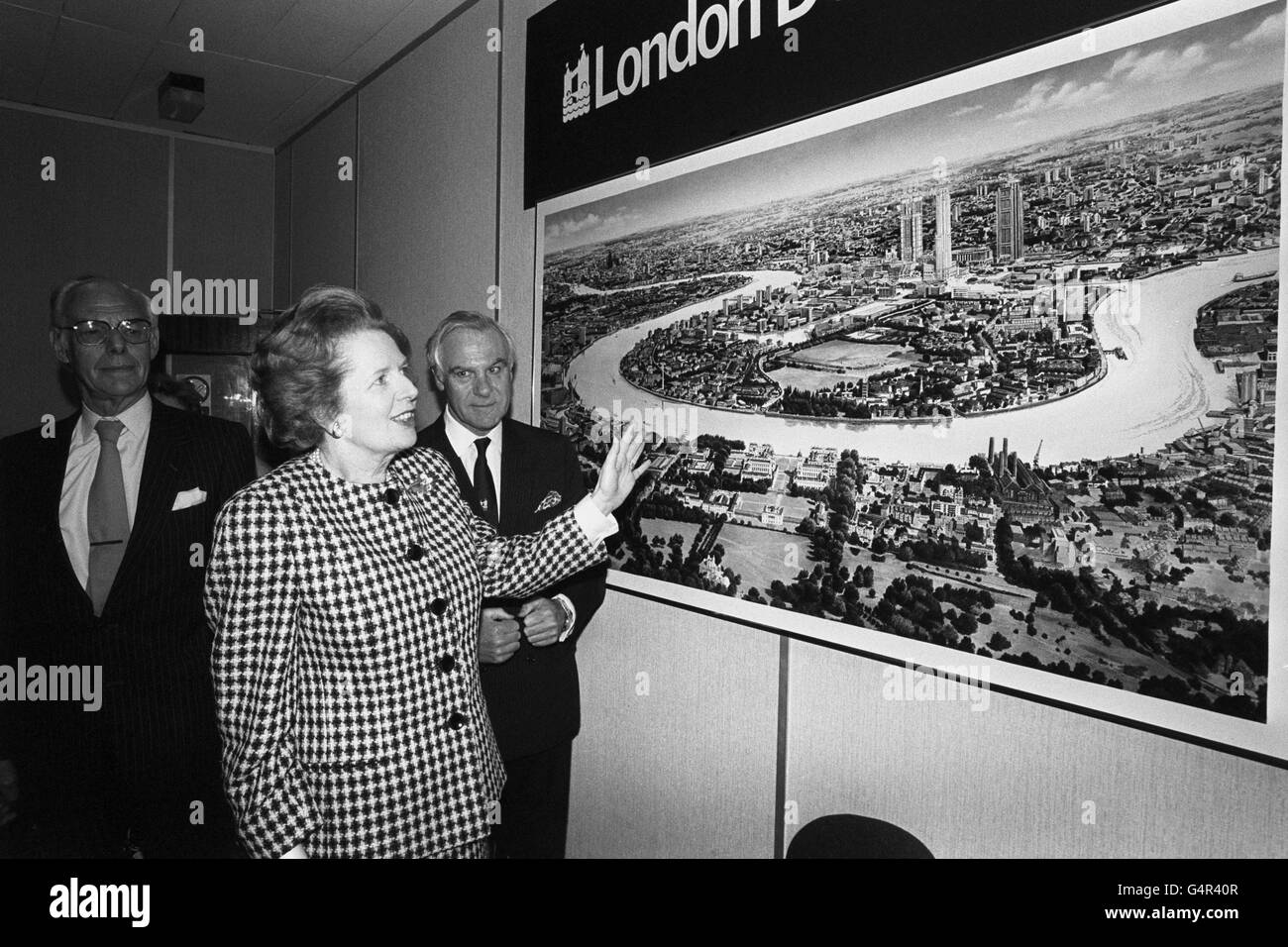 Premierministerin Margaret Thatcher diskutiert mit Chris Benson, dem Vorsitzenden der London Docklands Development Corporation am Hauptsitz in London, den Eindruck eines Künstlers von der zukünftigen Entwicklung im Hafengebiet. Auch Bilder (l) ist Denis Thatcher. Stockfoto