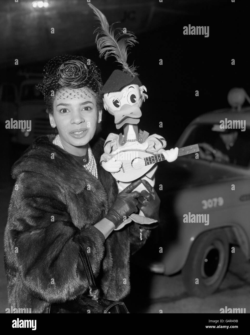 Sängerin Shirley Bassey mit einem Tiroler Donald Duck Maskottchen bei der Ankunft am Flughafen London aus Italien, wo sie in Mailand und im Fernsehen auftrat. Sie wird dieses Jahr Engagements bei Coventry, im britischen Fernsehen und eine Sommersaison in Bournemouth haben. Stockfoto