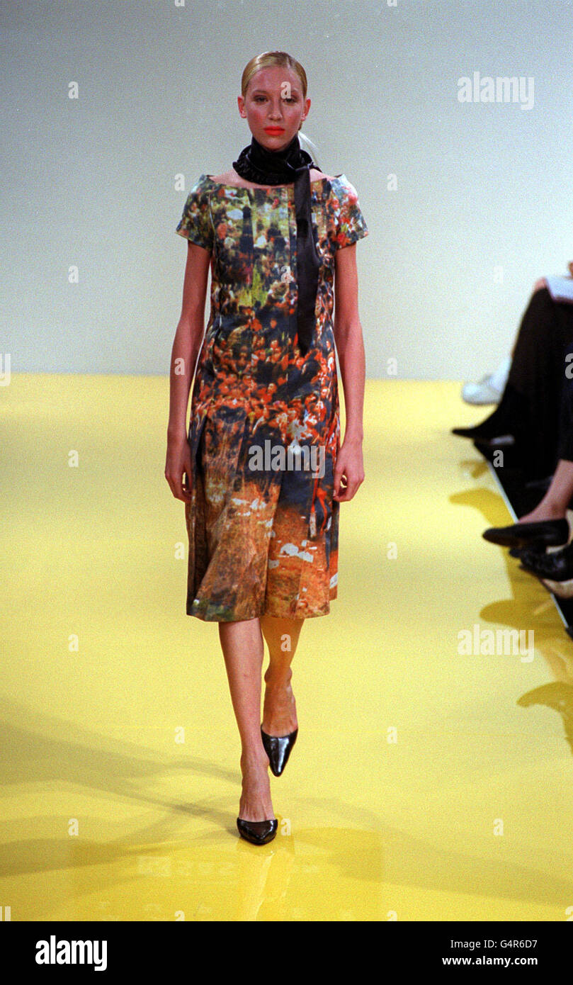 Ein Modell zeigt ein farbenfrohes Sommerkleid mit U-Ausschnitt und Fotoprint mit schwarzem Schal und schwarzen spitzen Schuhen als Teil der Markus Lupfer Kollektion für die London Fashion Week. Stockfoto