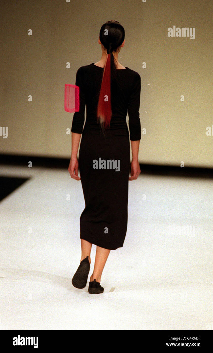 Die Rückansicht eines Models mit roten und weißen Haarverlängerung in einem Pferdeschwanz über einem langen schwarzen Kleid mit einem rosa Mesh-Würfelarmzubehör als Teil der New Zealand Four Kollektion für die London Fashion Week. Stockfoto