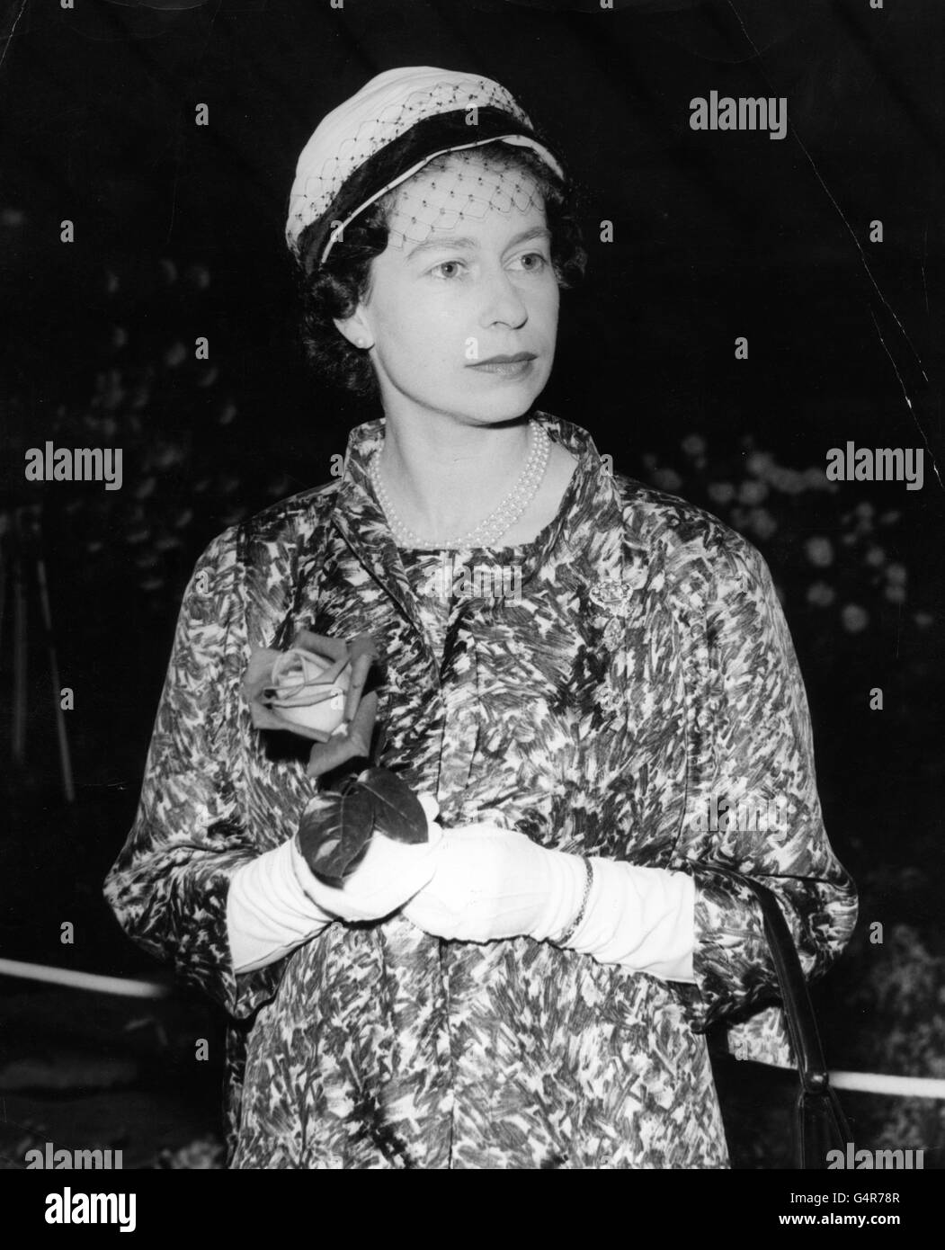 Königin Elizabeth II. Hält eine Rose, die ihr der bekannte Rosenbauer Harry Wheatcroft während ihrer Tour durch die Chelsea Flower Show auf dem Gelände des Royal Hospital in Chelsea, London, überreicht hat. Stockfoto