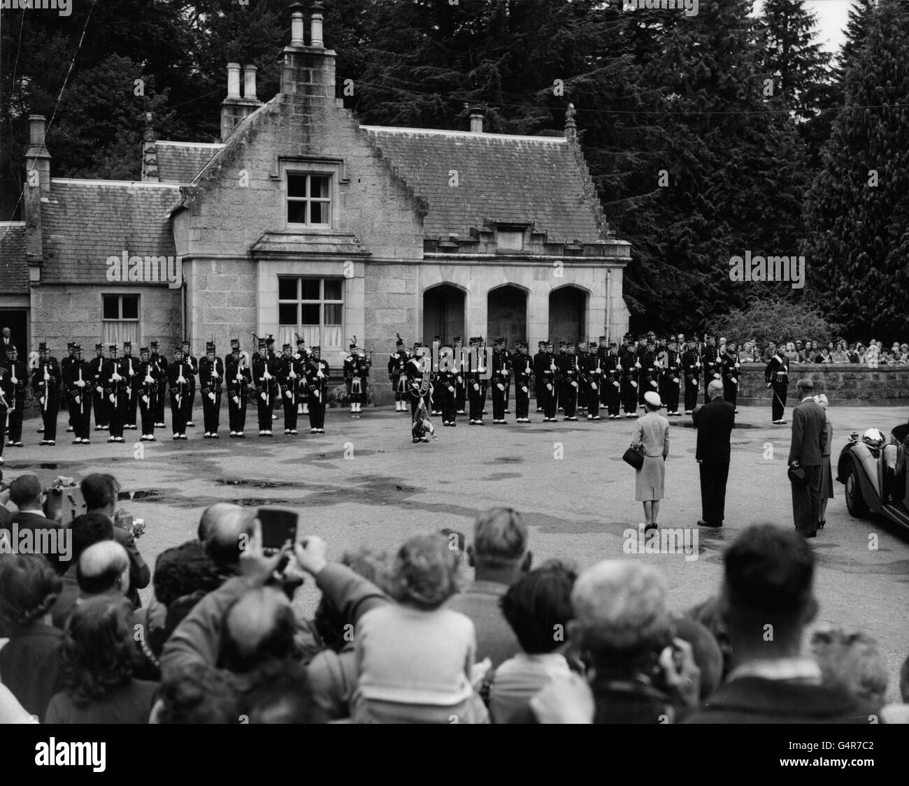 Der amerikanische Präsident Dwight D. Eisenhower steht mit Königin Elizabeth II., dem Herzog von Edinburgh, und Prinzessin Anne vor den Toren von Balmoral Castle, während bei seiner Ankunft die Nationalhymnen gespielt werden. Stockfoto