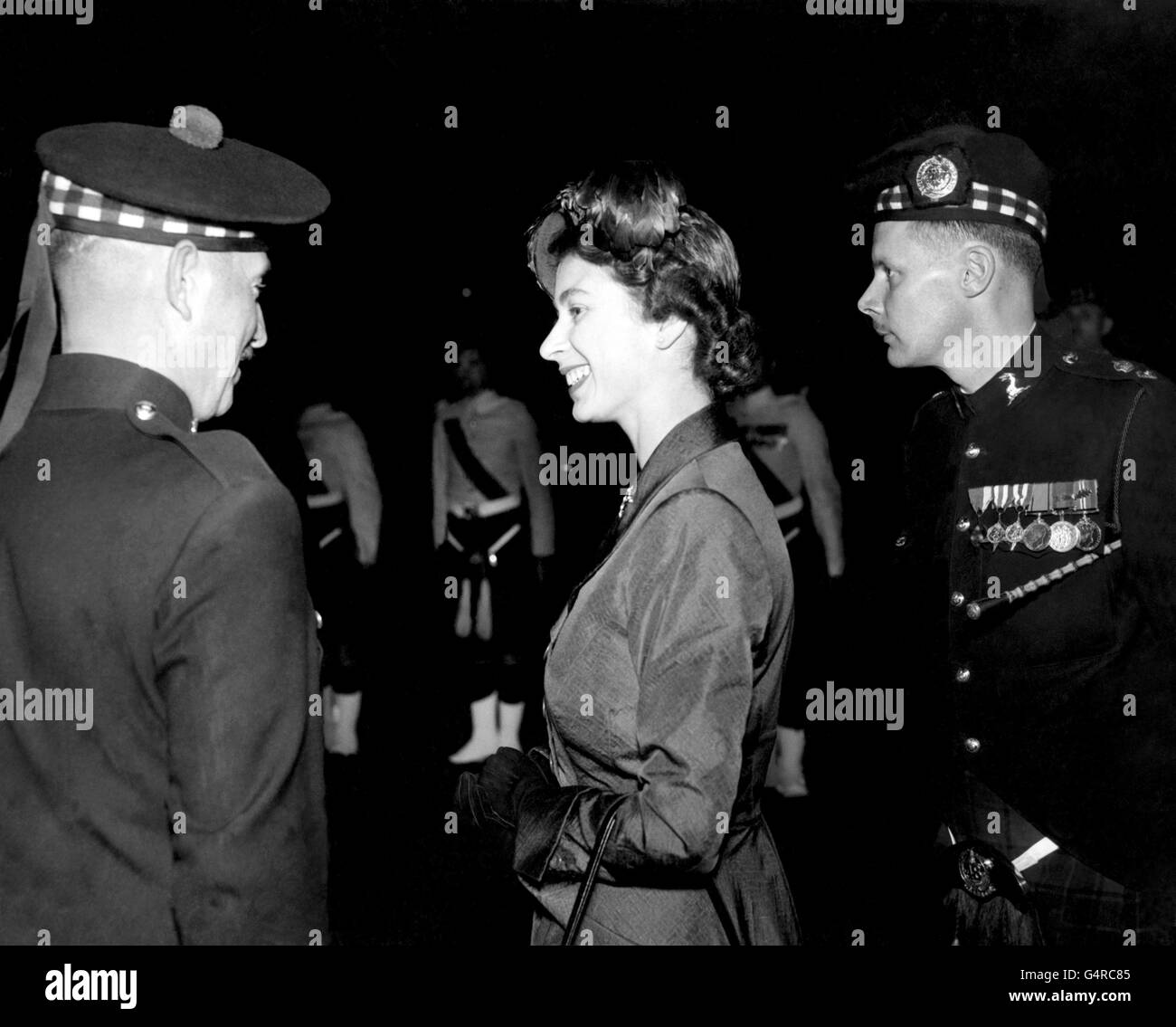 Prinzessin Elizabeth spricht lächelnd mit einem bonneted Mitglied eines kanadischen schottischen Regiments in den Armories in Hamilton, Ontario, die sie mit dem Herzog von Edinburgh während der Royal Tour of Canada besucht. Stockfoto