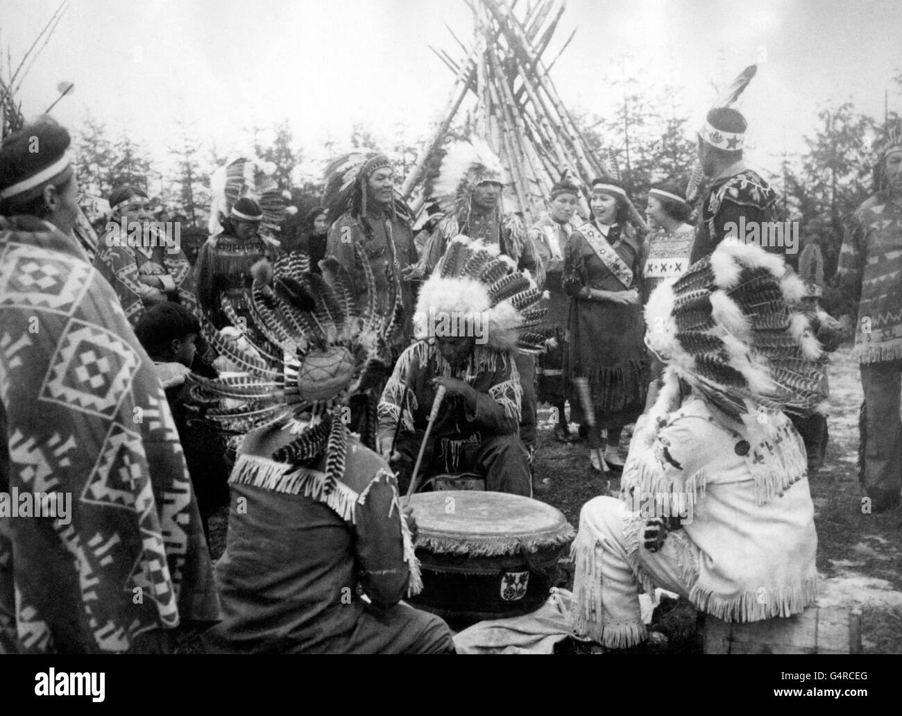 Ojibwy-Indianer haben während des Besuchs der Prinzessin Elizabeth und des Herzogs von Edinburgh in Port Arthur, Ontario, einen Zeltplatz mit Tipis, Toms und Friedensröhren eingerichtet. Stockfoto