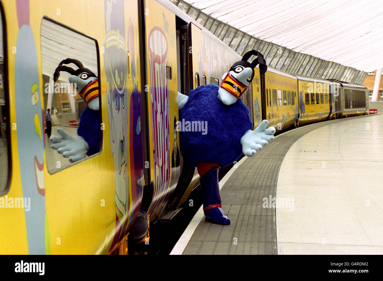 Ein Blue Meanie wird aus einem neu gestrichenen Euro Star-Zug am Bahnhof Waterloo in London gedrängt. Der Zug wurde mit Bildern aus dem umgestalteten Beatles-Film Yellow Submarine dekoriert und in Beatles Express umbenannt. Stockfoto