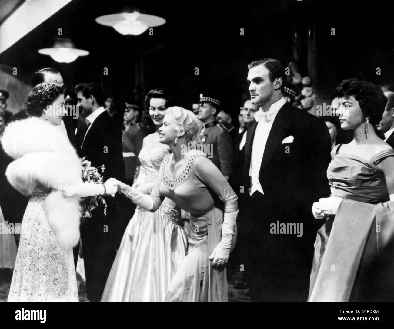 Queen Elizabeth II schüttelt die Hände mit der Hollywood-Schauspielerin Jayne Mansfield bei der Royal Film Performance von 'Les Girls' im Odeon, Leicester Square, London. Andere Stars, von links nach rechts, Anne Heywood, Stanley Baker und Dorothy Tutin. Stockfoto